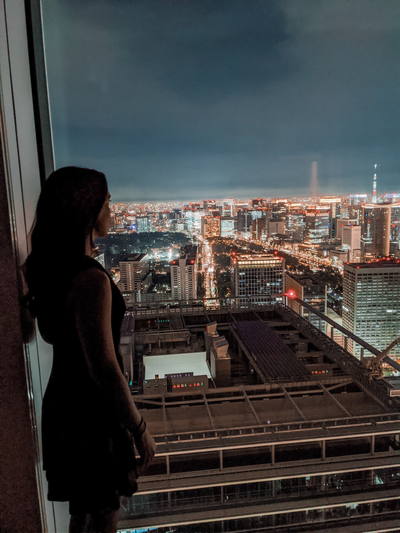 Woman standing on a balcony at night, overlooking Japan city lights
