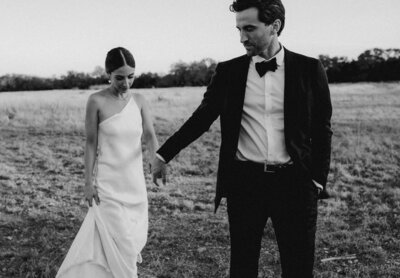 Groom holding brides hand as they walk across a field at prospect house wedding, Austin