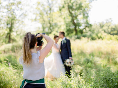 Photo from behind of Lauren Baker taking a photo of a bride and groom