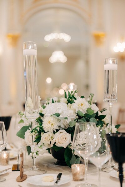 Elegant wedding table setting with floral centerpiece and tall candle holders, captured by a Luxury Wedding Photographer.