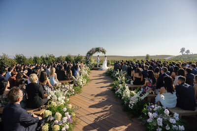 couple standing at wedding altar surrounded by purple  florals