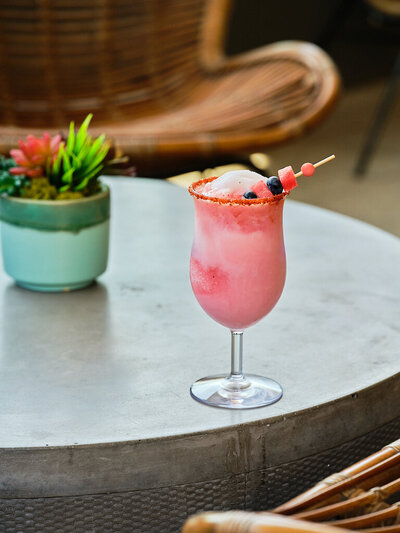 Picture of a pink blended cocktail on the rooftop patio of restaurant overlooking the city of Tempe Arizona