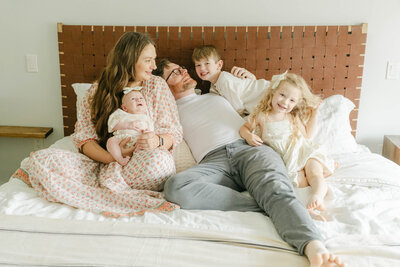 family of five cuddles on their bed with their newborn baby during a newborn session with AnneMarie Hamant