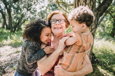 Happy family with twin toddlers sit in grass at sunset