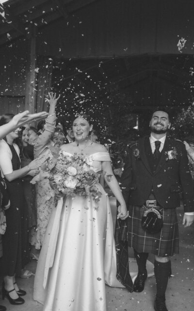 Couple joyfully walking through confetti, embracing their new journey together, capturing a moment of pure celebration and love on their special day.