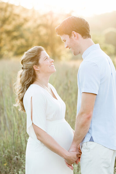 Expectant couple smile during outdoor maternity photo shoot with Julie Brock in Louisville KY park