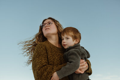Close up photos of mom holding her toddler son with the blue sky in the background
