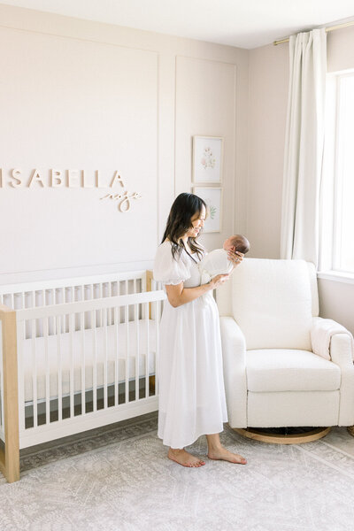 image of new mother standing in nursery with newborn baby taken by Newborn Photographer Sacramento Kelsey Krall
