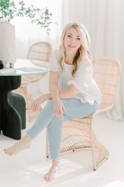 Nashville maternity photographer, Kristie Lloyd smiles as she sits in a chair at Blanc Studio West
