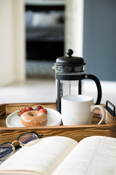 French Press coffee on a wood tray with a doughnut and strawberries
