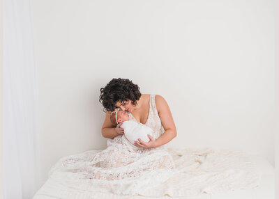 a mother with her newborn with all white clothes and background