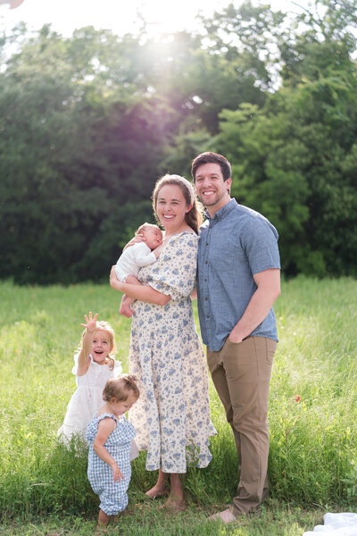 Family of 5 in field smiling with new baby son