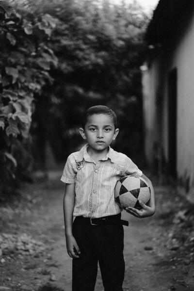 Jongetje met een bal onder de arm in een community wijk van Colombia