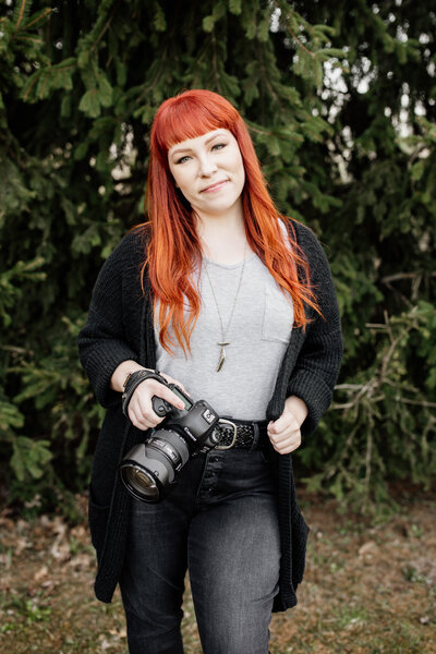 woman standing with her camera on her hip
