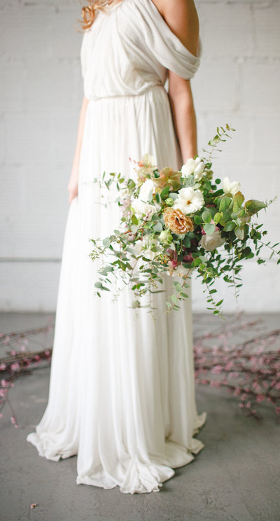 grecian wedding dress in concrete loft with beautiful floral bouquet