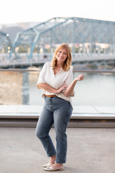 woman smiling while standing in front of chattanooga walking bridge