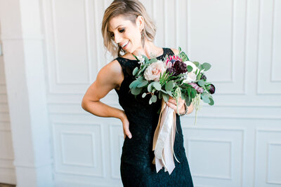 woman holding bouquet of flowers standing looking down in black dress