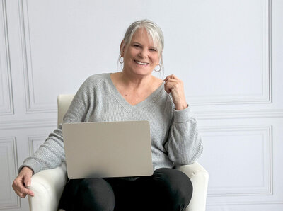 Portrait of  a woman in a grey sweater with a computer