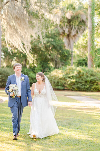 Bride and Groom walk through spanish moss in Charleston