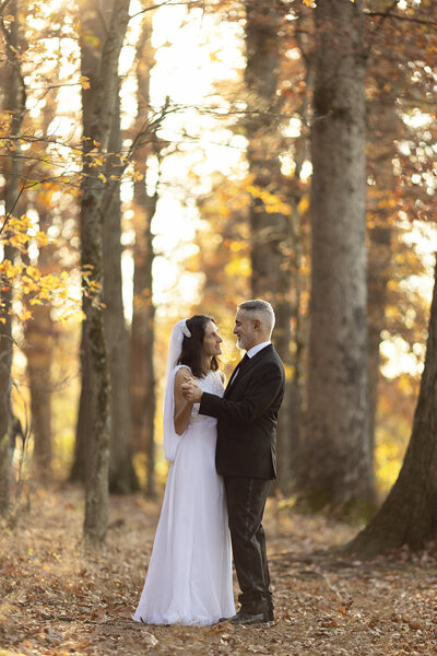 Married couple celebrating 25 years with recreated wedding portraits in wedding gown & tux taken in the Fall in an NJ park