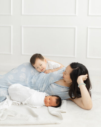 Mother poses with her newborn baby and older son