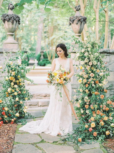 Stunning bride surrounded by beautiful floral arch holding bouquet