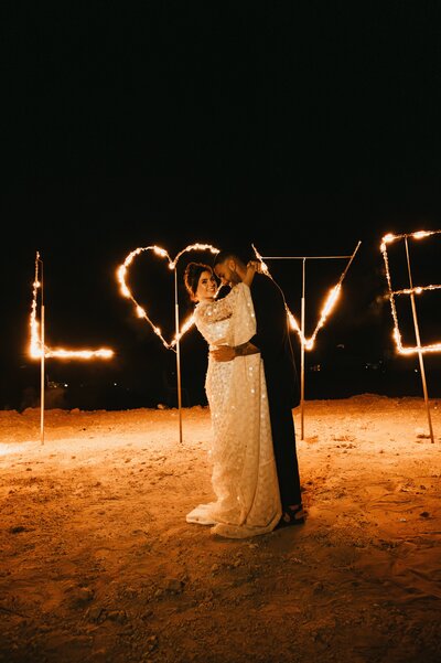 Megan and James in front dancing in front of fireworks after their desert wedding.