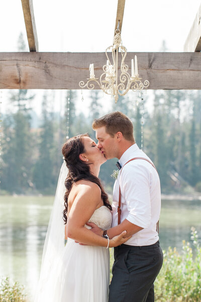 bride and groom kissing under an arch in the okanagan