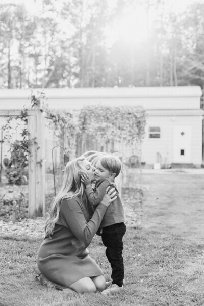 Mother kneels down to kiss son.