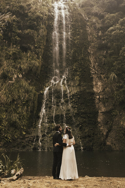 An elopement wedding portrait of a couple standing at a waterfall in Auckland by Eilish Burt Photography