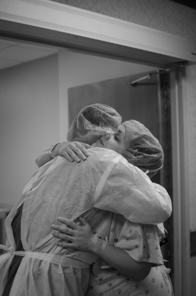 husband and wife embrace in scrubs before cesarean section
