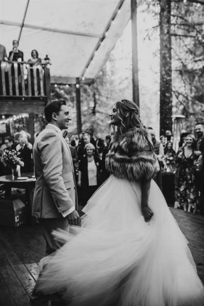 black and white photo of couple during first dance with brides swooshy wedding dress at Raven Glacier Lodge