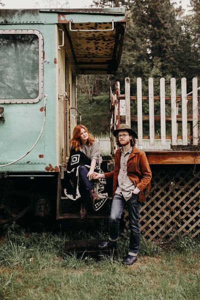 Woman hold her fiance's hand on the steps of an old train in Sequim, Washington