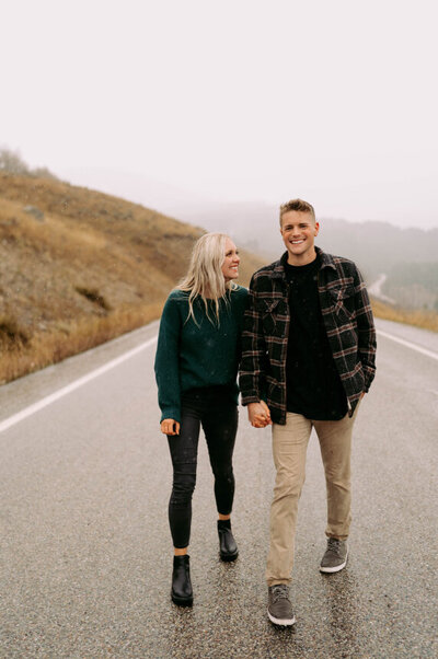 Man and woman walking on a road outside holding hands and smiling