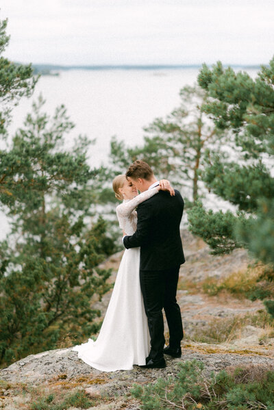 A wedding couple hugging in the forest. Seaside background in an image by wedding photographer Hannika Gabrielsson.