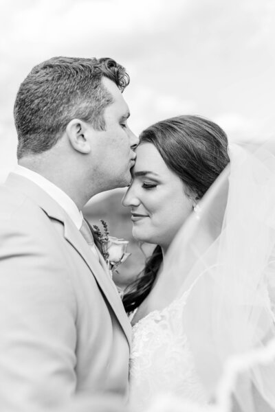 Groom kisses his wife's forehead