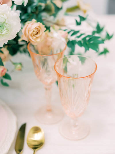 Beautiful pale peach glassware matches the pale peach and white florals for an elegant wedding dining experience.