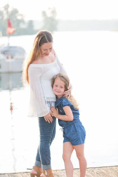 Mother embraces her daughter while standing on a dock