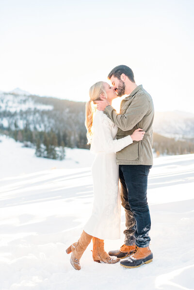 Couple kissing at sunset in the snowy mountains of Colorado.