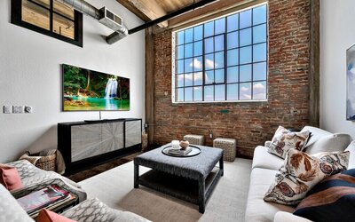 Living area with flat screen TV and exposed brick in this three-bedroom, two-bathroom vacation rental condo in the historic Behrens building in downtown Waco, TX.