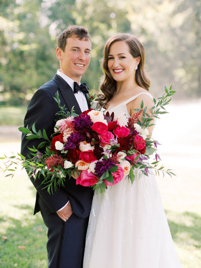 Bride and groom with large bridal bouquet with hotpink, pink and burgundy flowers