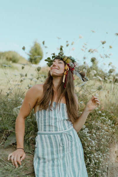 woman with leaf crown in field looking happy