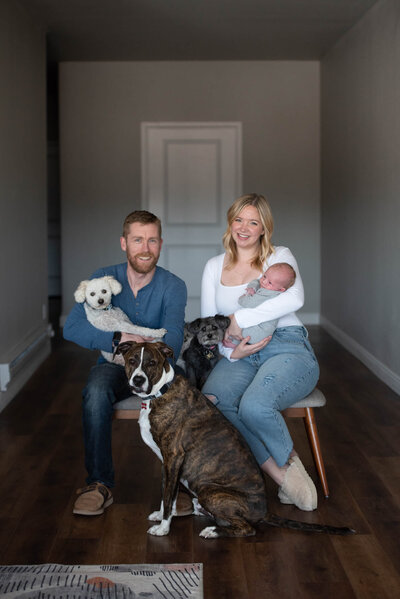 Couple holding their baby next to their dogs by Colorado Springs newborn photographer Jamie Smith