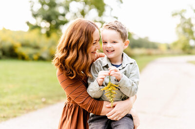 Mother holding smiling son at family session outside of Chicago, IL at Fabyan Forest Preserve.