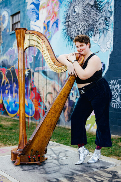 Harpist posing with their Harp in Downtown Asheville NC