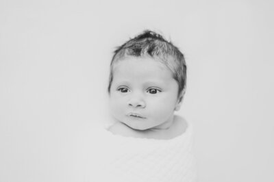 Black and white image of baby boy during studio newborn session