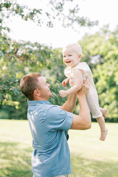 Dad lifts toddler son in the air in the summertime in Pennsylvania