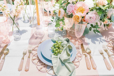 table decorated with florals , rose pink flatware and blue plates