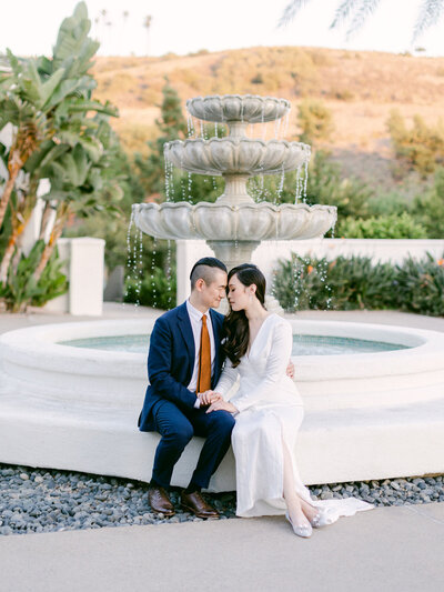Happy engagement couple sitting on fountain