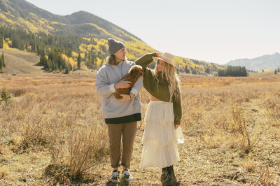 A couple poses with their adorable puppy amongst the fields and mountains of Crested Butte Colorado